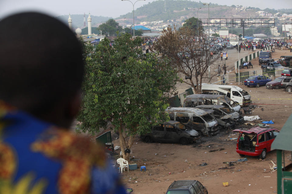 An man looks at burnt out cars and buses at the scene of an explosion at a bus park in Abuja, Nigeria, Tuesday, April. 15, 2014, with at least 72 feared dead as the blast destroyed more than 30 vehicles and caused secondary explosions as their fuel tanks exploded and burned. The attack just miles from Nigeria's seat of government increases doubts about the military's ability to contain an Islamic uprising that is dividing the country on religious lines as never before.(AP Photo/ Sunday Alamba)
