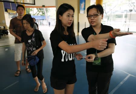 Voters queue to cast their ballots during the general election at a polling center in Singapore September 11, 2015. REUTERS/Edgar Su