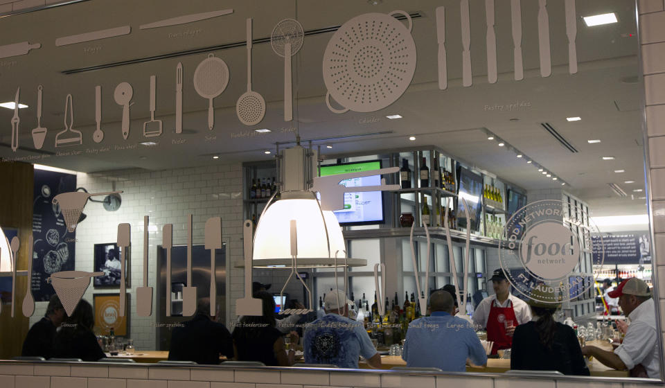 In this Wednesday, Nov. 14, 2012 photo, the interior of the Food Network Kitchen is seen in the reflection of a mirror at the Fort Lauderdale-Hollywood International Airport, in Fort Lauderdale, Fla. Dining-on-the-go is soaring at the airport where travelers can dine at a restaurant inspired by a test kitchen. The Fort Lauderdale-Hollywood International Airport is the first outpost in the nation to offer the Food Network Kitchen, designed to look much like what you would see in the cable network’s test kitchen: a butcher block bar counter, subway tiling, stainless steel surfaces and pots and pans hanging in a row behind a cash register. (AP Photo/J Pat Carter)