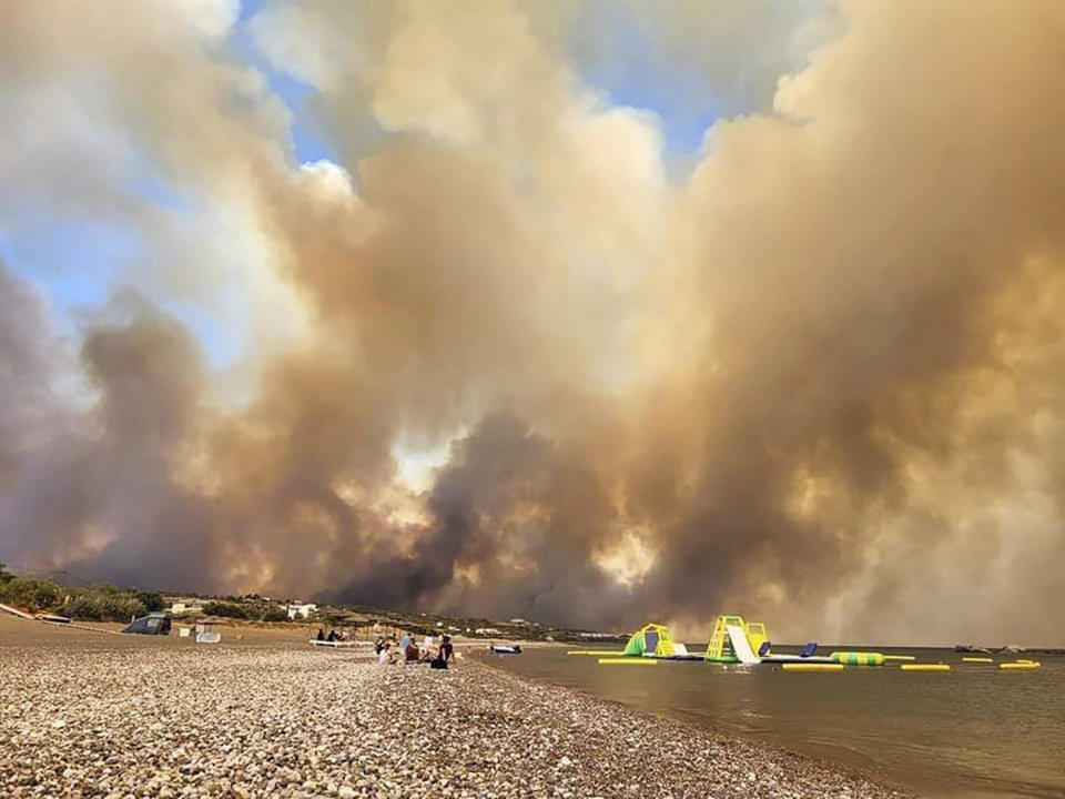Clouds of smoke from a forest fire rise to the sky on the island of Rhodes, Greece, Saturday, July 22, 2023. A large blaze burning on the Greek island of Rhodes for the fifth day has forced authorities to order an evacuation of four locations, including two seaside resorts. (Rhodes.Rodos via AP)