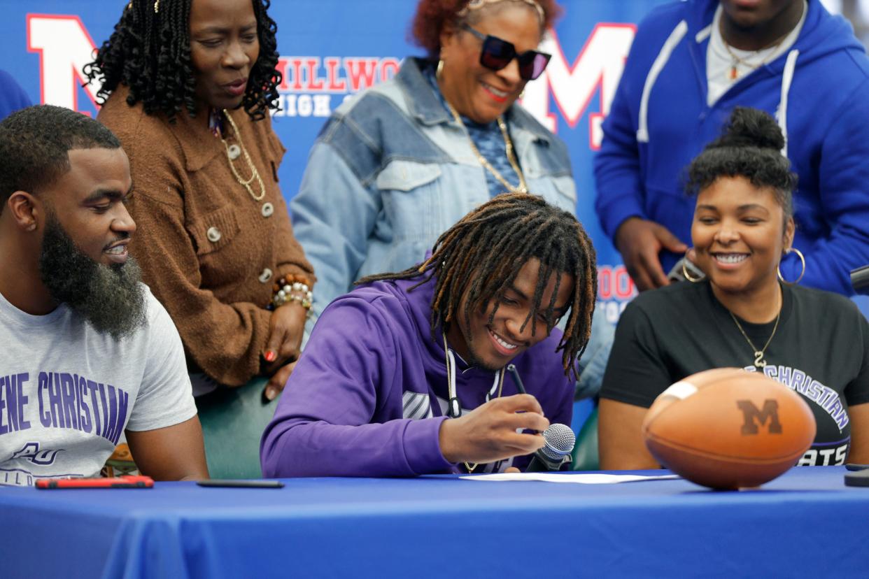 Millwood football player Micho Lavine is surrounded by his dad, Michael Lavine, left, and his mom, Devin Lolles, as he signs to play with Abilene Christian during a signing ceremony at Millwood High School in Oklahoma City, Wednesday, Feb. 7, 2024.