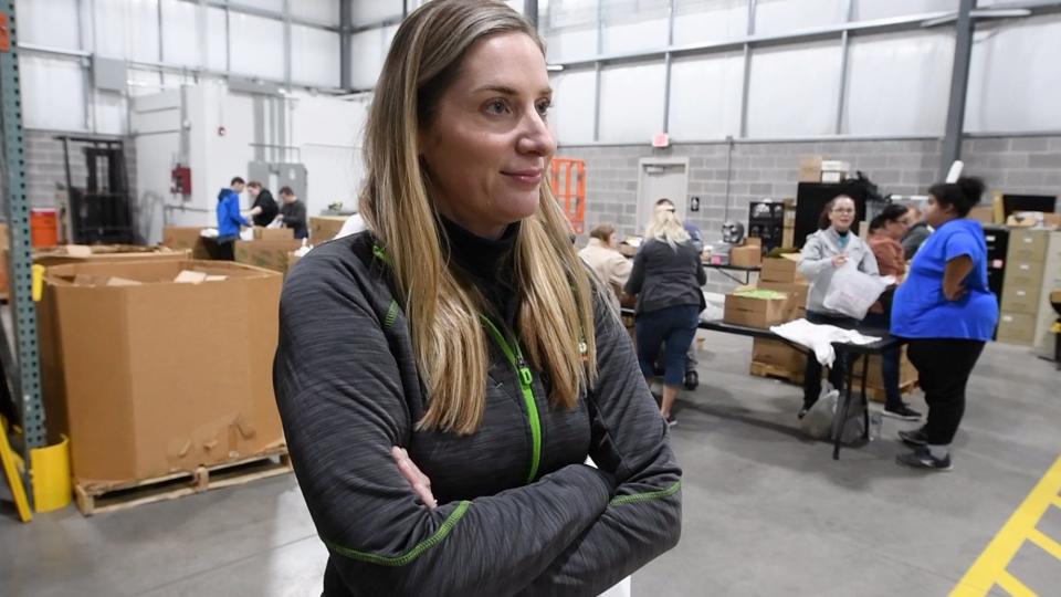 Jen Brillhart, president and CEO of the York County Food Bank, with food packers behind her at their Manchester Township warehouse.