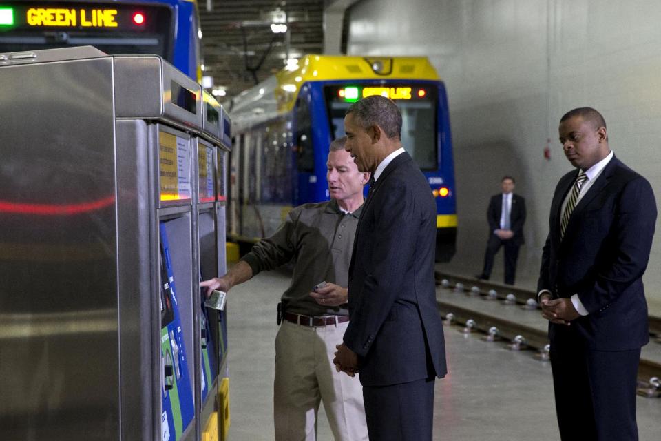 President Barack Obama and Transportation Secretary Anthony Foxx, right, listen as Mark Fuhrmann, New Start Program Director of Metro Transit, left, shows them a ticket vending machine during a tour of the Metro Transit Light Rail Operations and Maintenance Facility, Wednesday, Feb. 26, 2014, in St. Paul, Minn. In Minnesota Obama is expected to speak at Union Depot rail and bus station with a proposal asking Congress for $300 billion to update the nation's roads and railways, and about a competition to encourage investments to create jobs and restore infrastructure as part of the President’s Year of Action. (AP Photo/Jacquelyn Martin)