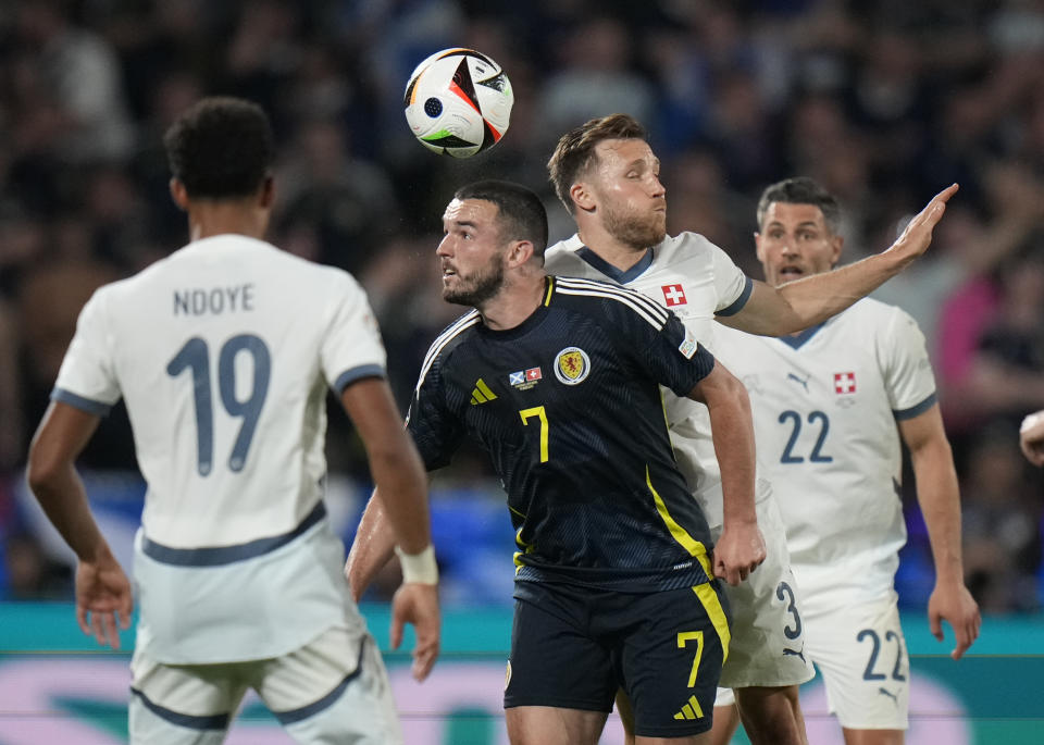 El escocés John McGinn y el suizo Silvan Widmer saltan por el balón durante el encuentro del Grupo A de la Eurocopa en Colonia, Alemania el miércoles 19 de junio del 2024. (AP Foto/Alessandra Tarantino)