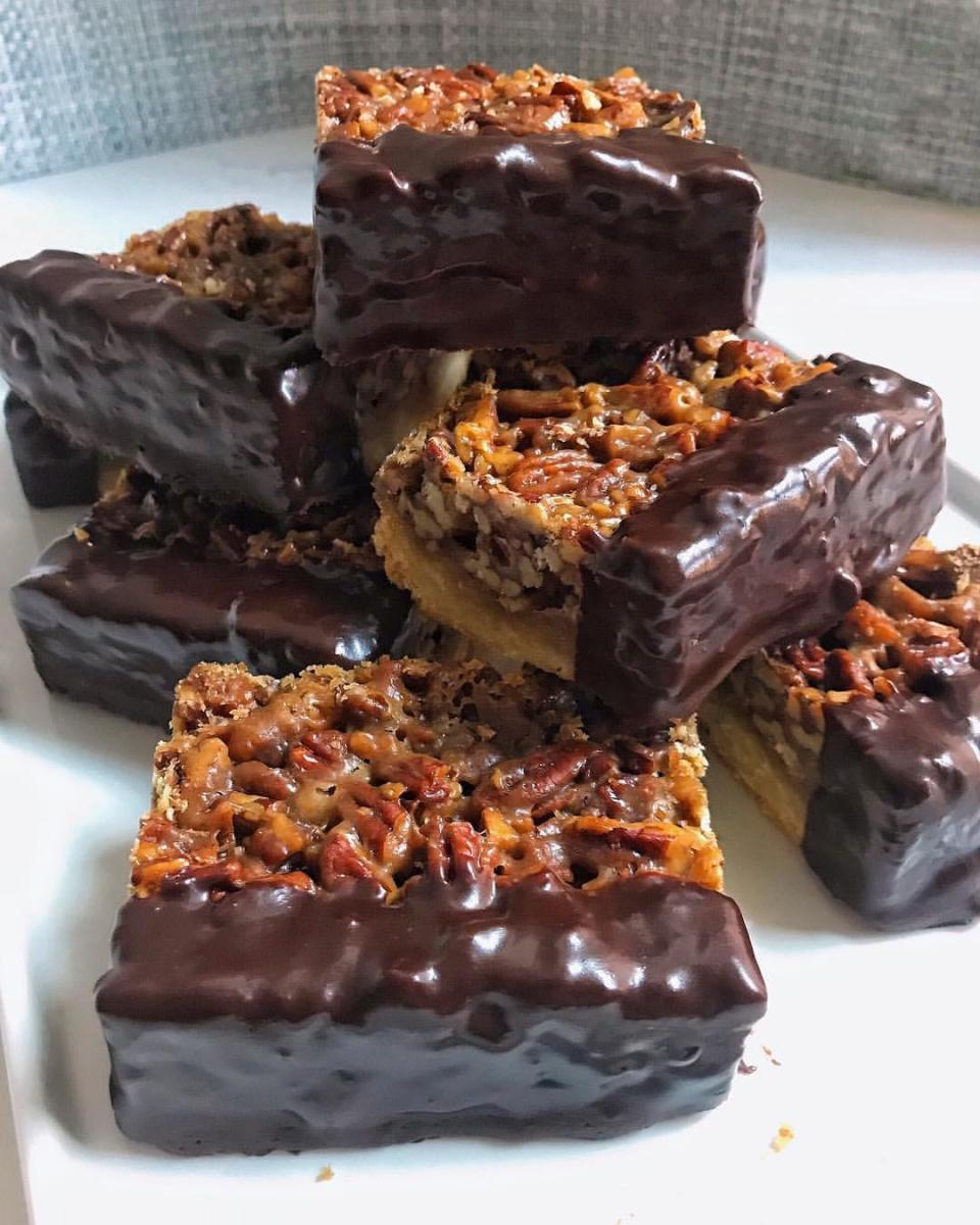Pecan squares dipped halfway in chocolate in a stack