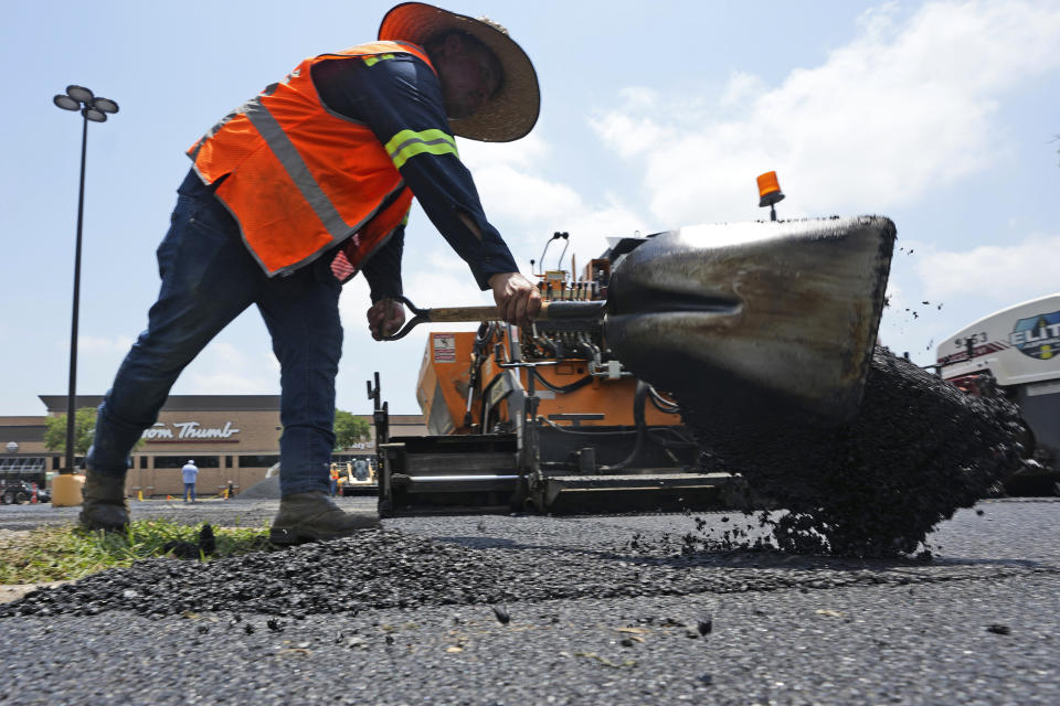 File - A worker shovels hot asphalt during a parking lot resurfacing job in Richardson, Texas, on June 20, 2023. The U.S. job market has remained resilient, but Americans are facing higher prices and more expensive credit with the Federal Reserve hiking benchmark interest rates to combat inflation. (AP Photo/LM Otero, File)