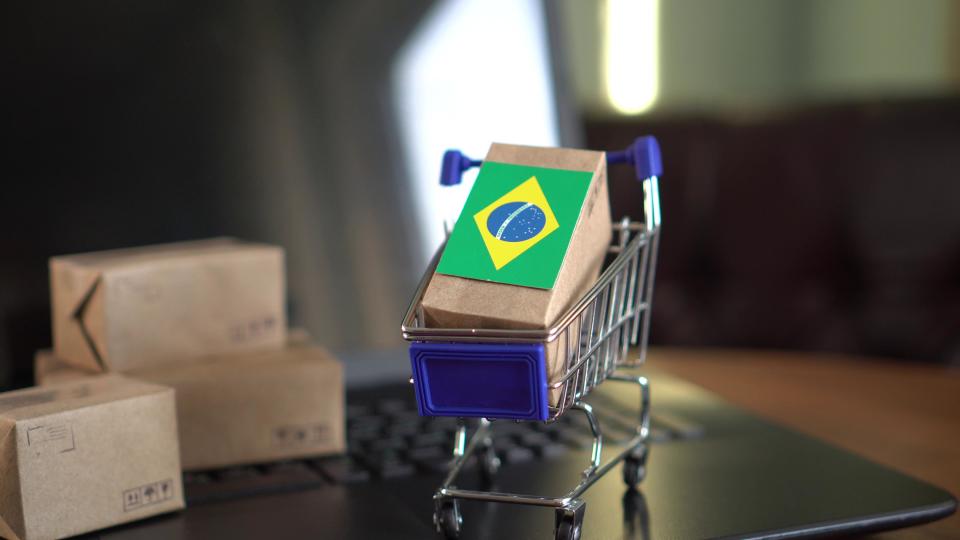 Tiny boxes and cart on computer with Brazilian flag.