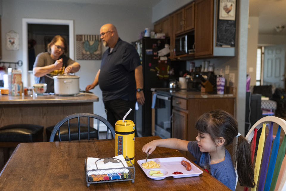Madison Schroeder, 4, eats her lunch while her grandparents prepare food in their kitchen in Fruita, Colo., April 28, 2024. (Kelsey Brunner for The Washington Post)