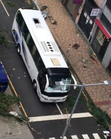 A bus drives past tree branches and debris along a street in Macau during Typhoon Hato, in this still image taken from social media video obtained by Reuters August 24, 2017. Deo Carmel Viste/via REUTERS