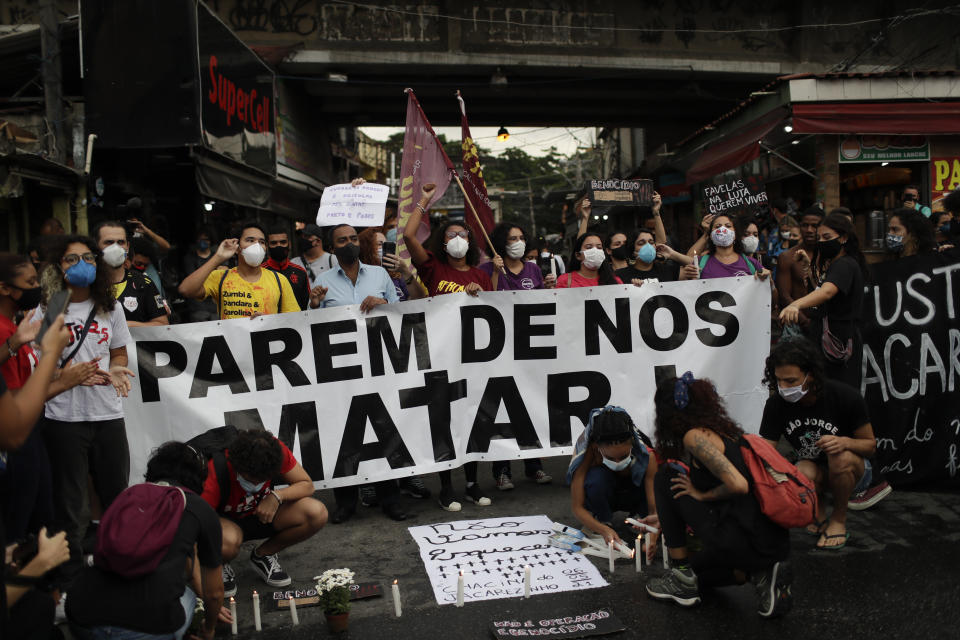 Activistas y parientes de víctimas encienden velas y sostienen una manta con la leyenda: "Dejen de matarnos" el viernes 7 de mayo de 2021, al día siguiente de un letal operativo policial en la favela de Jacarezinho, Río de Janeiro. (AP Foto/Silvia Izquierdo)