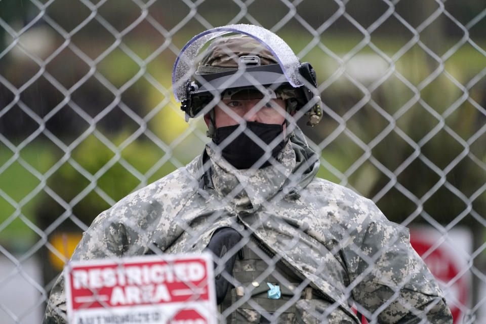 A member of the Washington National Guard stands at a fence surrounding the Capitol in anticipation of protests Monday, Jan. 11, 2021, in Olympia, Wash. State capitols across the country are under heightened security after the siege of the U.S. Capitol last week. (AP Photo/Ted S. Warren)