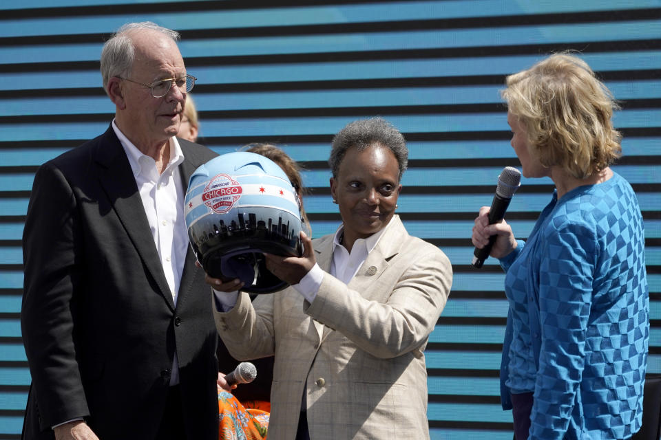 NASCAR CEO Jim France, left, and Executive Vice President Lesa Kennedy, right, present Chicago Mayor Lori Lightfoot with a racing helmet Tuesday, July 19, 2022, in Chicago after a news conference where the racing body announced a Cup Series street race to be held July 2, 2023, in the city. (AP Photo/Charles Rex Arbogast)