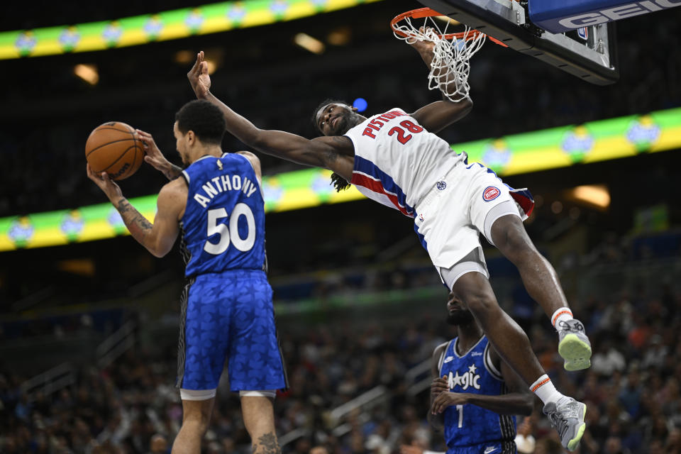 Detroit Pistons center Isaiah Stewart (28) hangs from the rim after missing a dunk as Orlando Magic guard Cole Anthony (50) grabs the rebound during the first half of an NBA basketball game, Sunday, March 3, 2024, in Orlando, Fla. (AP Photo/Phelan M. Ebenhack)