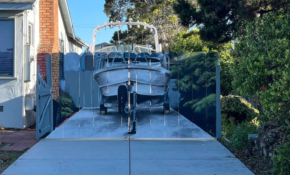 Etienne Constable's 19-foot Arima Sea Ranger sits in his driveway in Seaside, California, behind a fence featuring a hyper-realistic mural of the boat.