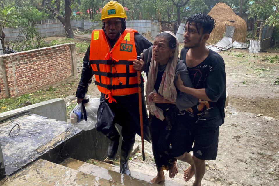 Rescue workers help an elderly woman to reach a makeshift shelter after a storm in Teknaf, near Cox's Bazar, Bangladesh, Sunday, May 14, 2023. Bangladesh and Myanmar braced Sunday as a severe cyclone started to hit coastal areas and authorities urged thousands of people in both countries to seek shelter. (AP Photo/Al-emrun Garjon)