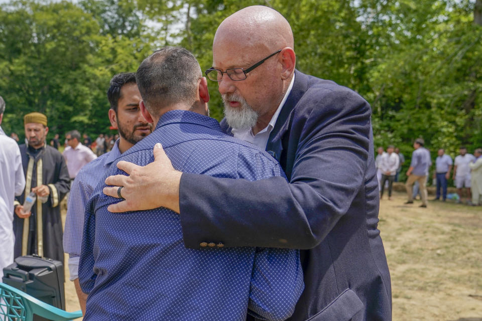 Matt Butler, right, who served with Nasrat Ahmad Yar, 31, in Afghanistan, speaks with Ahmad Yar's friends and family during a funeral at the All Muslim Association of America cemetery on Saturday, July 8, 2023 in Fredericksburg, Va. Ahmad Yar, an Afghan immigrant who worked as an interpreter for the U.S. military in Afghanistan, was shot and killed on Monday, July 3, while working as a ride-share driver in Washington. (AP Photo/Nathan Howard)