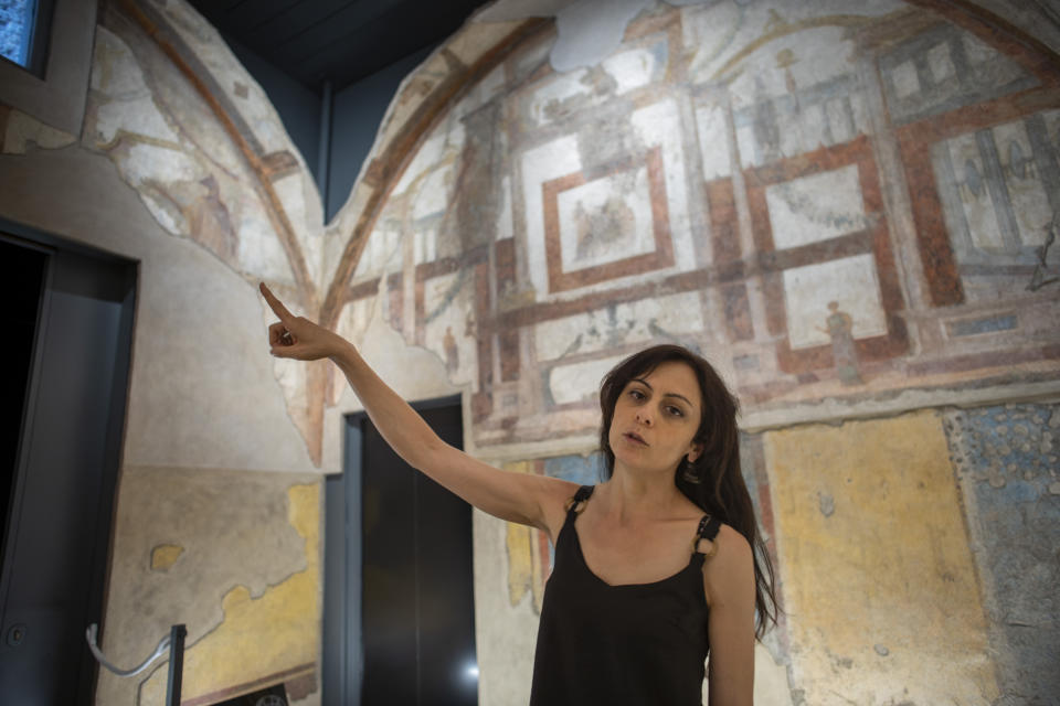 Archaeologist Silvia Fortunati describes to journalists the frescoes coming from the sacellum, a small votive chapel, of a two-story home, or "Domus," dating from around 134-138 AD that was partially destroyed to make way for the construction of the Caracalla public baths, which opened in 216 AD, are on display at the Caracalla archaeological park in Rome, Thursday, June 23, 2022. The frescoed ceiling and walls of a domestic temple honoring Greco-Roman and Egyptian religious deities and believed to have belonged to a wealthy merchant family were first discovered in the mid-19th century about 10 meters (yards) underneath the current ground level of the baths, had been briefly exhibited but has been closed to the public for 30 years. (AP Photo/Domenico Stinellis)