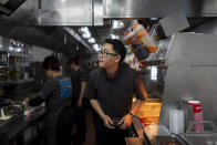 Lawrence Cheng, whose family owns seven Wendy's locations south of Los Angeles, works in the kitchen at his Wendy's restaurant in Fountain Valley, Calif., June 20, 2024. Cheng used to have nearly a dozen employees at his Fountain Valley location during the day. Now, he only schedules seven for each shift as he scrambles to absorb a dramatic jump in labor costs after a new California law boosted the hourly wage for fast food workers on April 1 from $16 to $20 an hour. (AP Photo/Jae C. Hong)