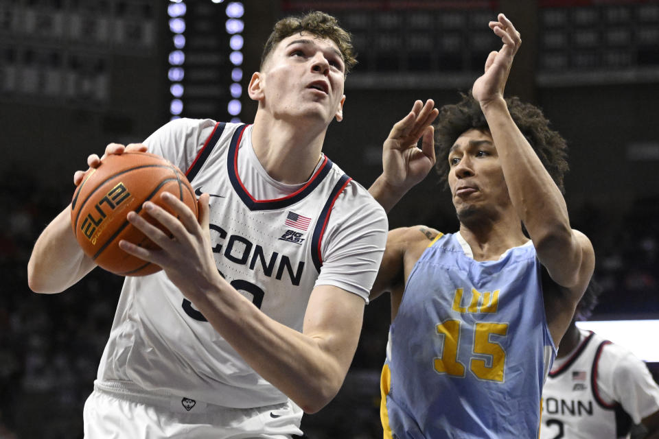 Connecticut's Donovan Clingan, left, drives to the basket as Long Island's C.J. Delancy defends during the first half of an NCAA college basketball game, Saturday, Dec. 10, 2022, in Storrs, Conn. (AP Photo/Jessica Hill)