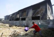 A labourer works beside a gutted slipper factory in Valenzuela, Metro Manila in the Philippines May 14, 2015. A fire at a factory making rubber slippers killed 31 workers in the Philippine capital on Wednesday, and dozens were missing and feared dead, officials said. REUTERS/Erik De Castro