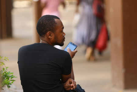 FILE PHOTO: A man checks his mobile phone in Harare, Zimbabwe, January 18, 2019. REUTERS/Philimon Bulawayo/File Photo