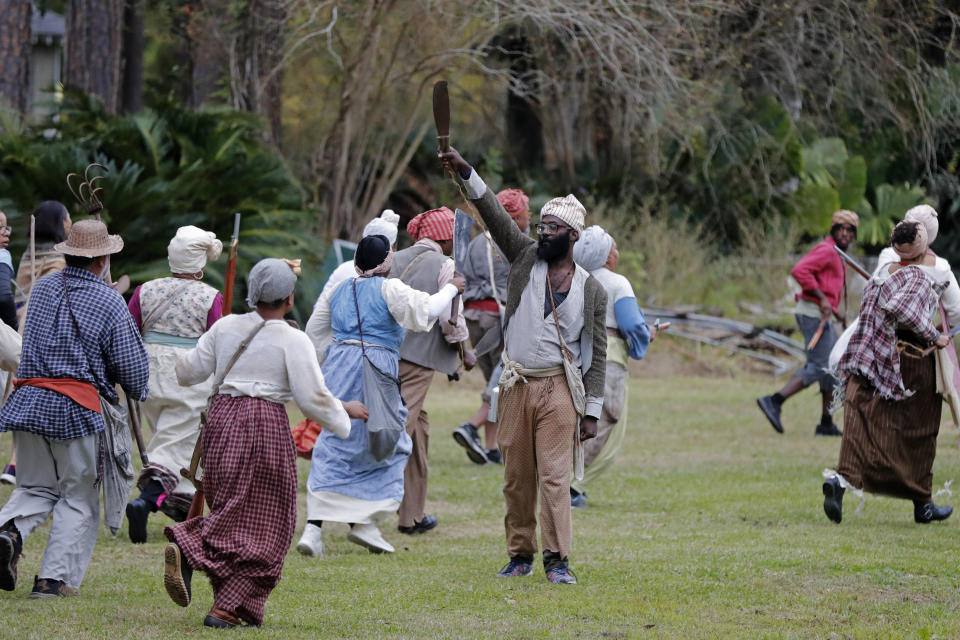 People participate in a performance artwork reenacting the largest slave rebellion in U.S. history in LaPlace, La., Friday, Nov. 8, 2019. The reenactment was conceived by Dread Scott, an artist who often tackles issues of racial oppression and injustice. Scott says that those who took part in the 1811 rebellion were "heroic" and that the rebellion is something that people should know about and be inspired by. (AP Photo/Gerald Herbert)