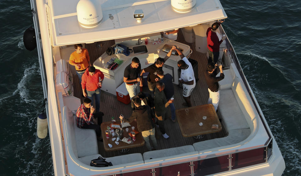 Tourists party on a yacht in Dubai, United Arab Emirates, Tuesday, Jan. 12, 2021. Since becoming one of the world's first destinations to open up for tourism, Dubai has promoted itself as the ideal pandemic vacation spot. With peak tourism season in full swing, coronavirus infections are surging to unprecedented heights, with daily case counts nearly tripling in the past month, but in the face of a growing economic crisis, the city won't lock down and can't afford to stand still. (AP Photo/Kamran Jebreili)