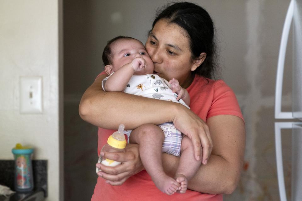 Yury Navas, 29, of Laurel, Md., kisses her two-month-old son, Ismael Galvaz, after making him a bottle of formula with the only formula he can take without digestive issues, Enfamil Infant, from her dwindling supply of formula at their apartment in Laurel, Md., Monday, May 23, 2022. After this day's feedings she will be down to their last 12.5 ounce container of formula. Navas doesn't know why her breastmilk didn't come in for her third baby and has tried many brands of formula before finding the one kind that he could tolerate well, which she now says is practically impossible for her to find. To stretch her last can she will sometimes give the baby the water from cooking rice to sate his hunger. (AP Photo/Jacquelyn Martin)