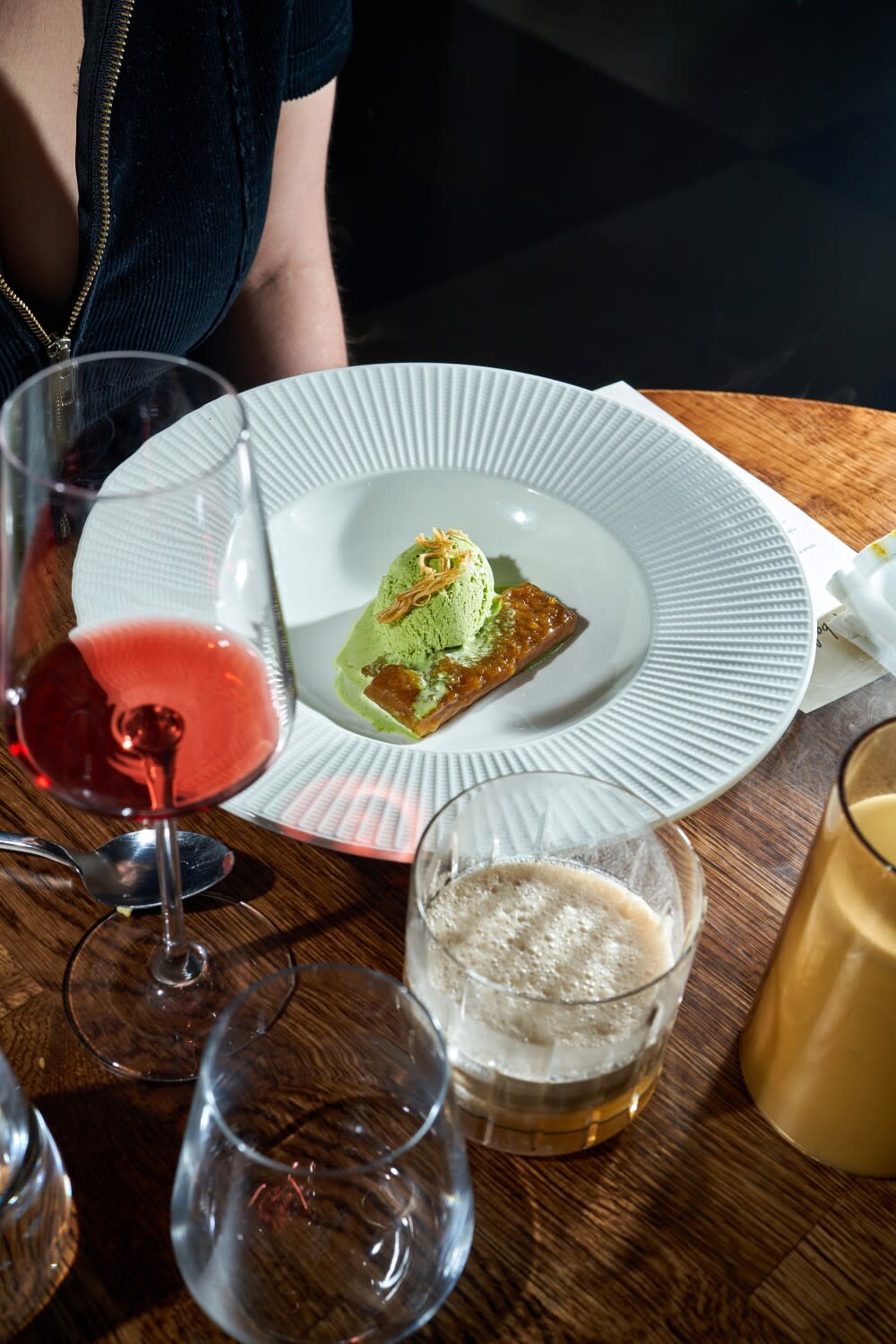 A plate containing a scoop of green ice cream atop a rectangular tart.