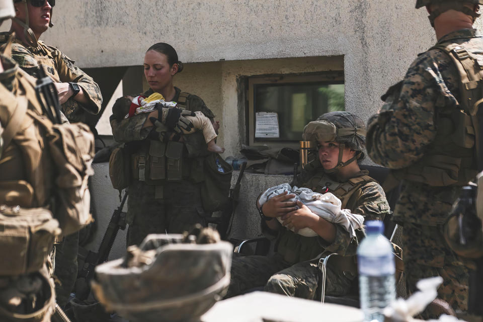 In this image provided by the U.S. Marine Corps, Marines assigned to the 24th Marine Expeditionary Unit (MEU) calm infants during an evacuation at Hamid Karzai International Airport in Kabul, Afghanistan, Friday, Aug. 20, 2021. (Sgt. Isaiah Campbell/U.S. Marine Corps vi AP)