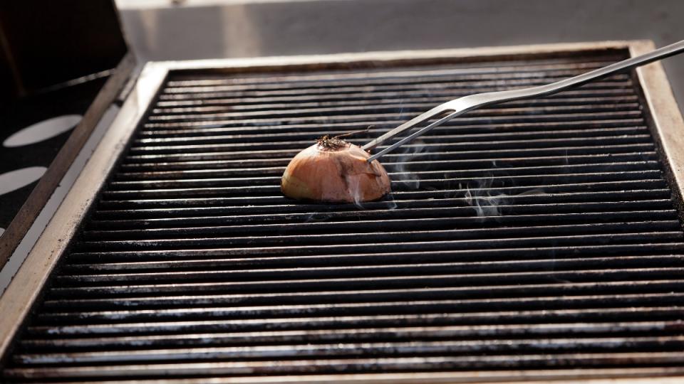 An onion being used to clean a grill grate