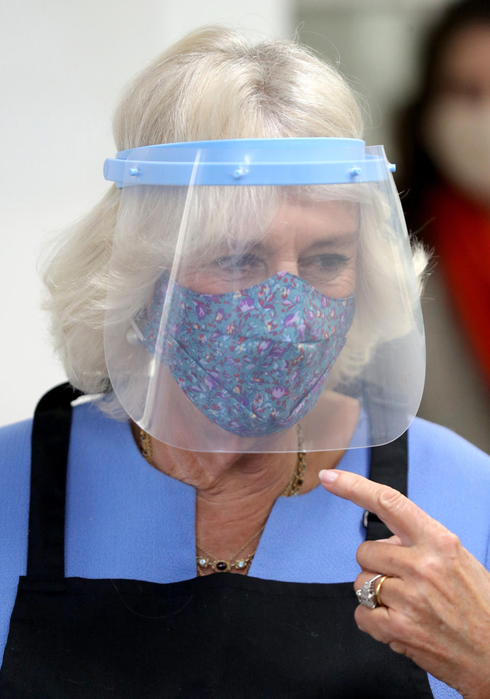 RICKMANSWORTH, ENGLAND - OCTOBER 08: Camilla, Duchess of Cornwall, in her role as President of the Royal Voluntary Service, wears a face shield as she helps serving meals during a visit to The Royal Voluntary Service Lunch Club on October 8, 2020 in Rickmansworth, England. (Photo by Andrew Matthews - WPA Pool/Getty Images)