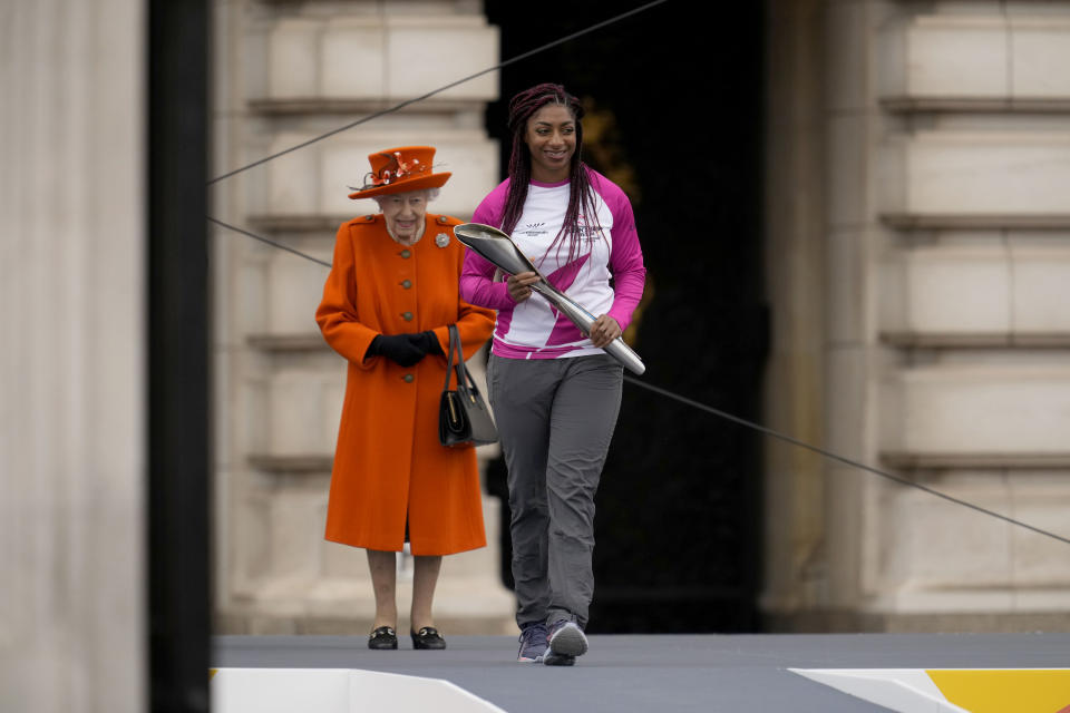 Baton bearer Britain's Kadeena Cox, who won two gold medals at the Rio 2016 Paralympic Games, receives the baton from Britain's Queen Elizabeth II at the Birmingham 2022 Commonwealth Games Queen's Baton Relay event outside Buckingham Palace in London, Thursday, Oct. 7, 2021. The city of Birmingham in England will host the 2022 Commonwealth Games. (AP Photo/Matt Dunham)