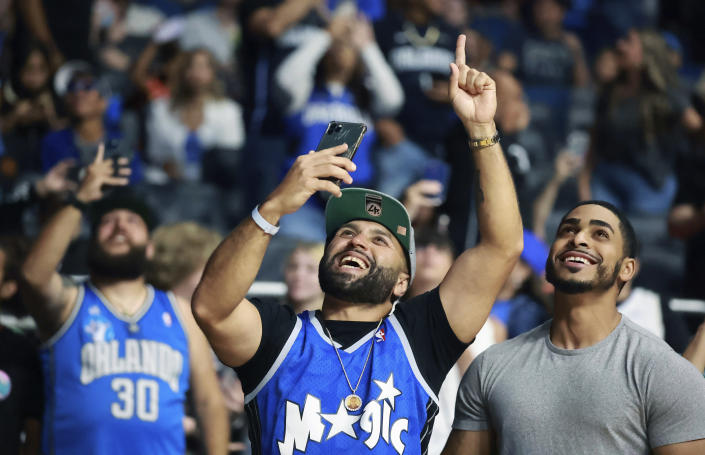 David Nejad, middle, and other fans react during an NBA basketball draft watch party after the Orlando Magic selected Duke's Paolo Banchero with the first pick in the draft Thursday, June 23, 2022. (Stephen M. Dowell/Orlando Sentinel via AP)