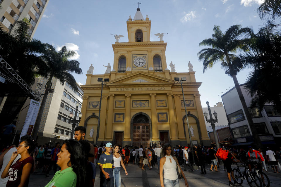 People walk outside the Metropolitan Cathedral after a fatal shooting in Campinas, Brazil, Tuesday, Dec. 11, 2018. A man opened fire in the cathedral in southern Brazil after Mass on Tuesday, killing four and leaving four others injured before taking a bullet in the ribs in a firefight with police and then shooting himself in the head, authorities said. (AP Photo/Victor R. Caivano)