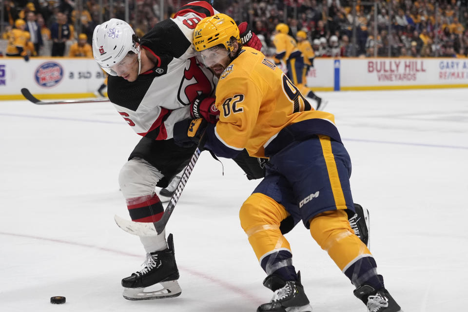 New Jersey Devils defenseman John Marino (6) and Nashville Predators center Tommy Novak (82) battle for a loose puck during the second period of an NHL hockey game Tuesday, Feb. 13, 2024, in Nashville, Tenn. (AP Photo/George Walker IV)