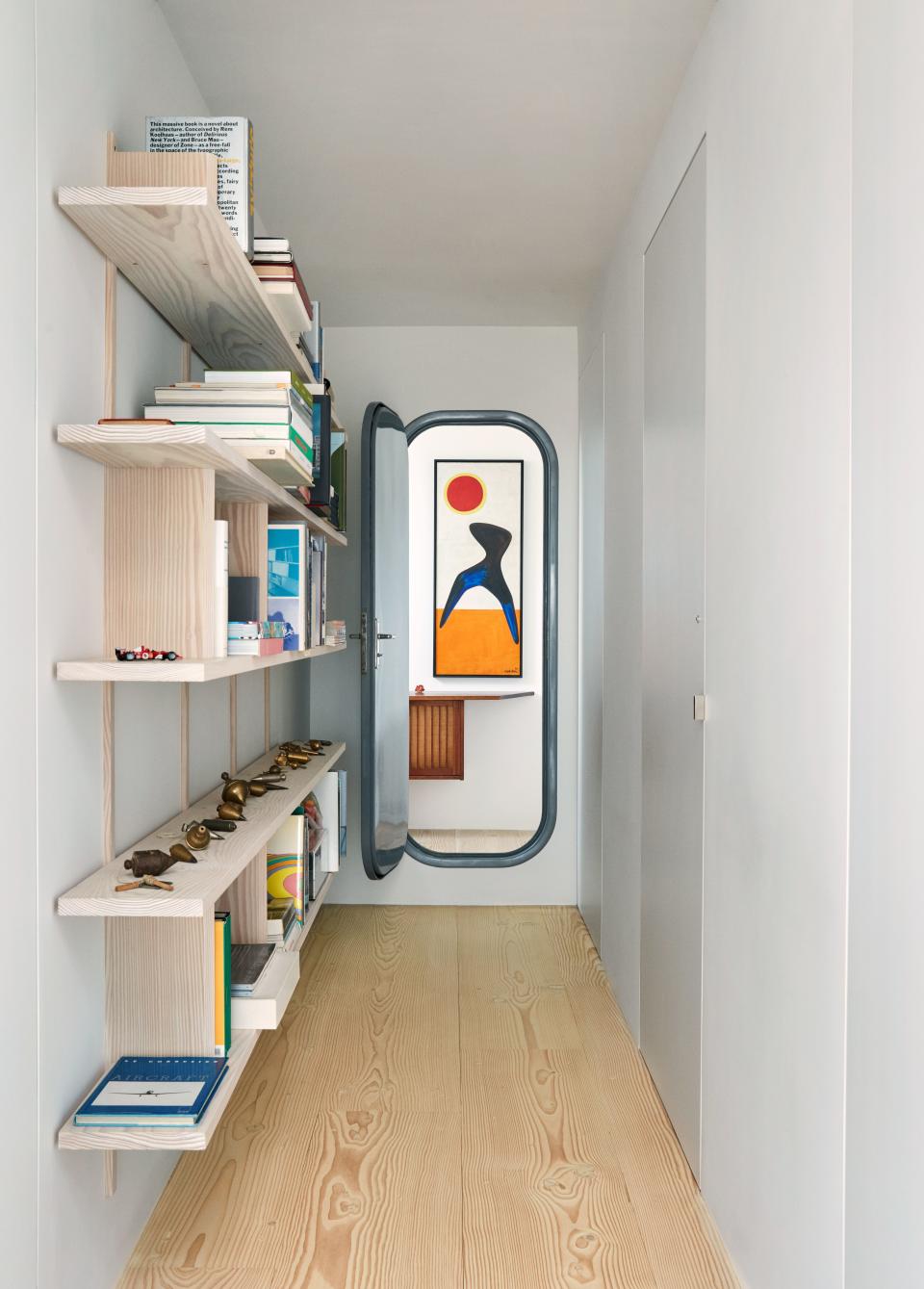 A vintage Charlotte Perriand door leads to a tiny chamber, within which an Alexander Calder painting hangs above a wall-hung George Nakashima cabinet.