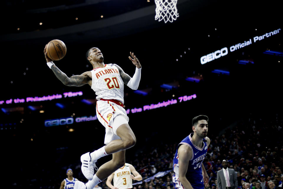 Atlanta Hawks' John Collins, left, goes up for a dunk against Philadelphia 76ers' Furkan Korkmaz during the first half of an NBA basketball game, Monday, Feb. 24, 2020, in Philadelphia. (AP Photo/Matt Slocum)