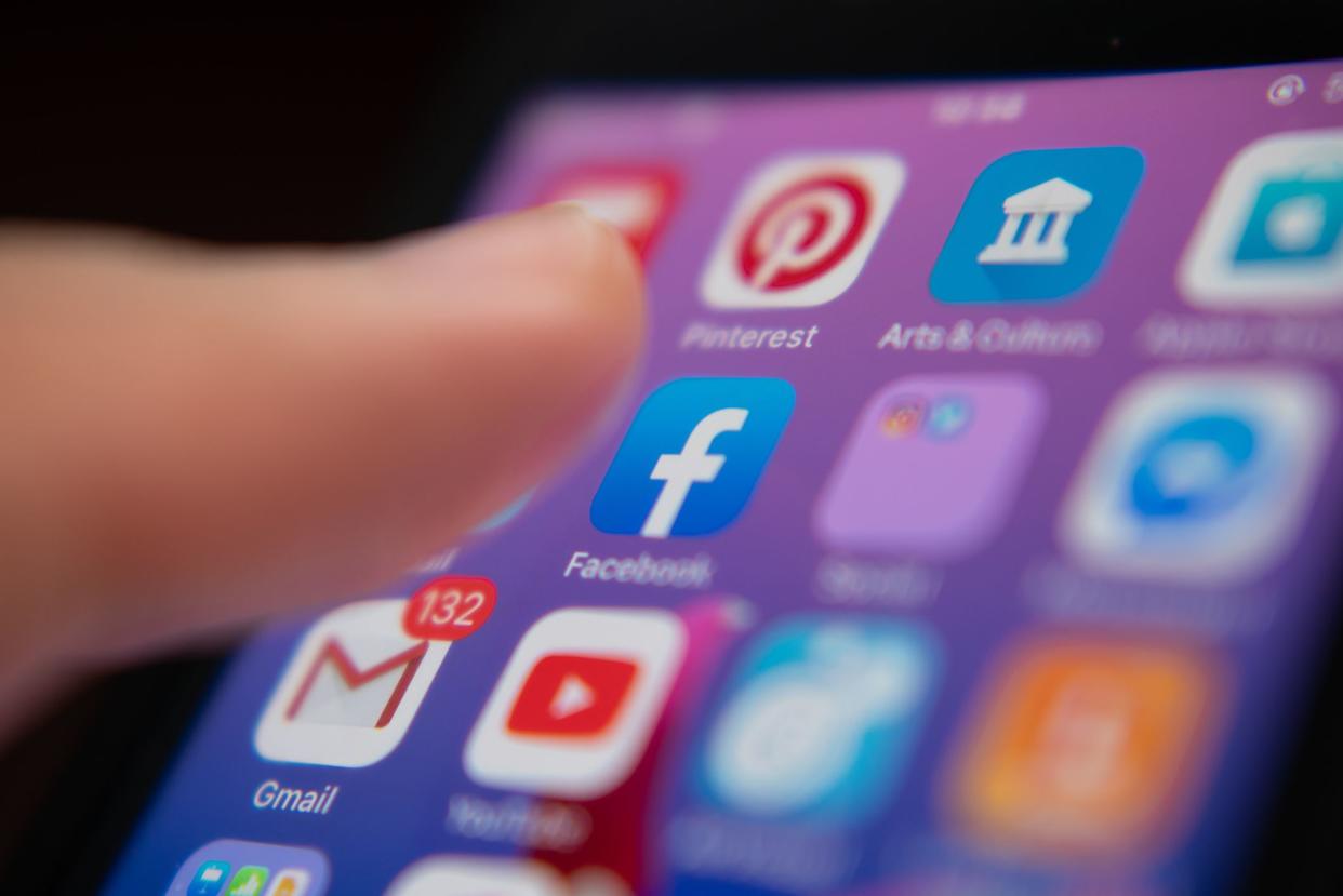 Bangkok, Thailand - July 13, 2019 : iPhone user touching Facebook logo on iPhone screen to open the app.