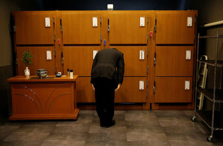 An undertaker from a funeral company bows to Yasuhiro Sato's casket after placing the casket in the morgue in Tokyo, Japan, September 13, 2017. REUTERS/Toru Hanai