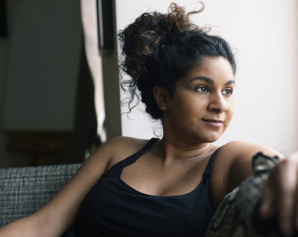 A woman is sitting on a couch looking out the window