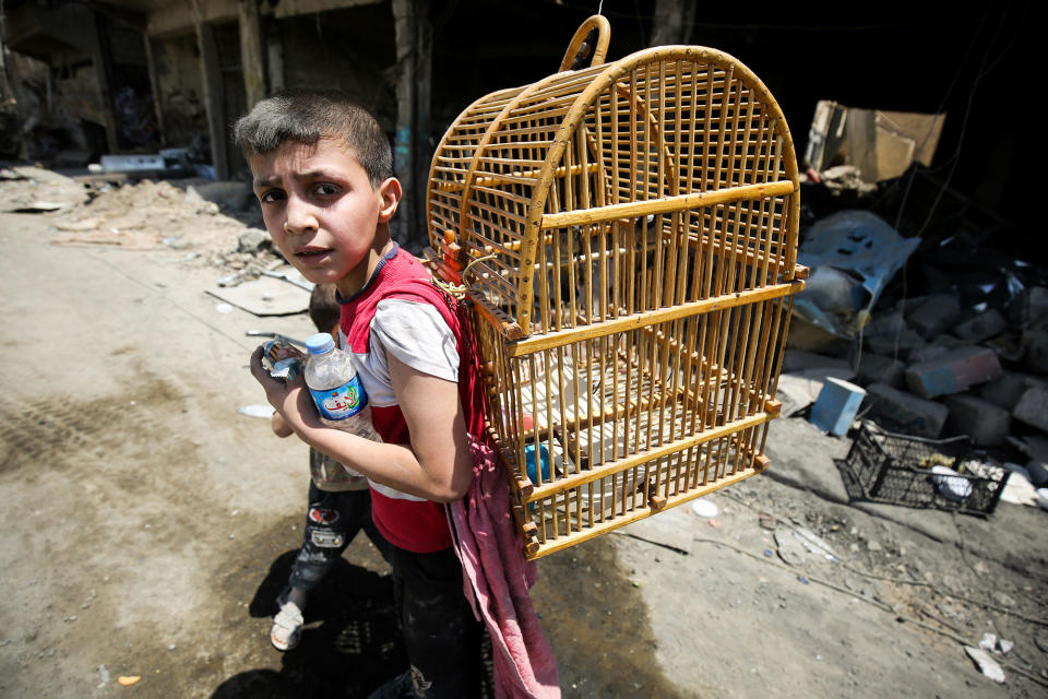 <p>An Iraqi boy carries a birdcage on his back as he flees from the Old City of Mosul on June 20, 2017 during the ongoing offensive by Iraqi forces to retake the last district still held by the Islamic State (IS) group. (Photo: Ahmad al-Rubaye/AFP/Getty Images) </p>