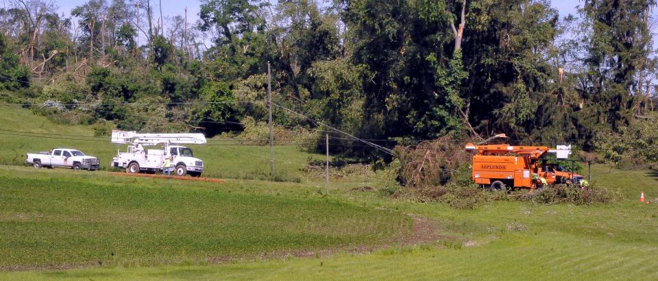 Power crews wait while a tree-trimming crew takes trees off the lines.