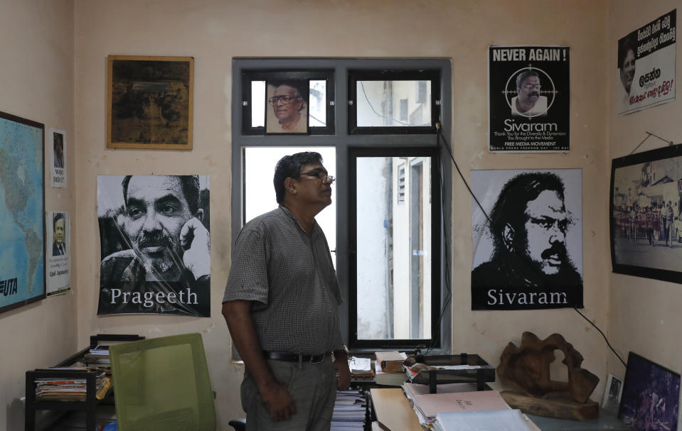 In this Nov. 6, 2019 photo, Sri Lankan media rights activist Udaya Kalupathirana stands in his office looking at posters of Sri Lankan journalists who had been allegedly tortured by groups of government soldiers during the last stages of president Mahinda Rajapaksa's regime in Colombo, Sri Lanka. Forced to flee their country a decade ago to escape allegedly state-sponsored killer squads, Sri Lankan journalists living in exile doubt they’ll be able to return home soon or see justice served to their tormentors _ whose alleged ringleader could come to power in this weekend’s presidential election. Exiled journalists and media rights groups are expressing disappointment over the current government’s failure in punishing the culprits responsible for crimes committed against media members. (AP Photo/Eranga Jayawardena)