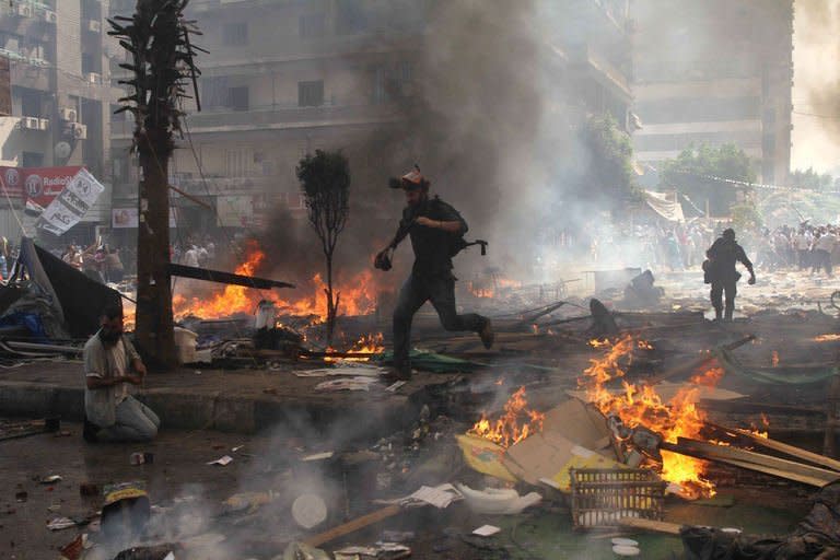 Reporters run for cover during clashes between Muslim Brotherhood supporters of Egypt's ousted president Mohamed Morsi, and police in Cairo on August 14, 2013