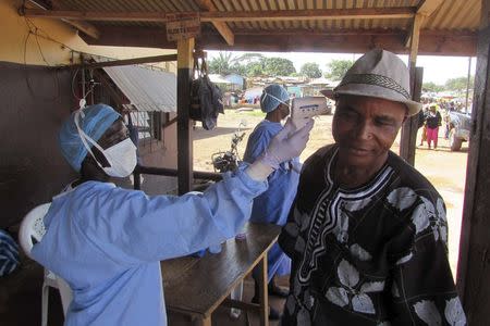 A health worker checks the temperature of a man at a roadside health checkpoint outside Ganta October 7, 2014. REUTERS/Daniel Flynn