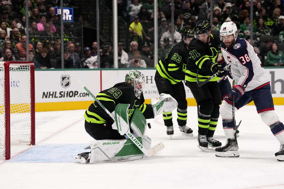 Dallas Stars goaltender Jake Oettinger (29) attempts to glove a shot as center Tyler Seguin (91) helps against pressure from Columbus Blue Jackets center Boone Jenner (38) in the second period of an NHL hockey game, Monday, Oct. 30, 2023, in Dallas. (AP Photo/Tony Gutierrez)