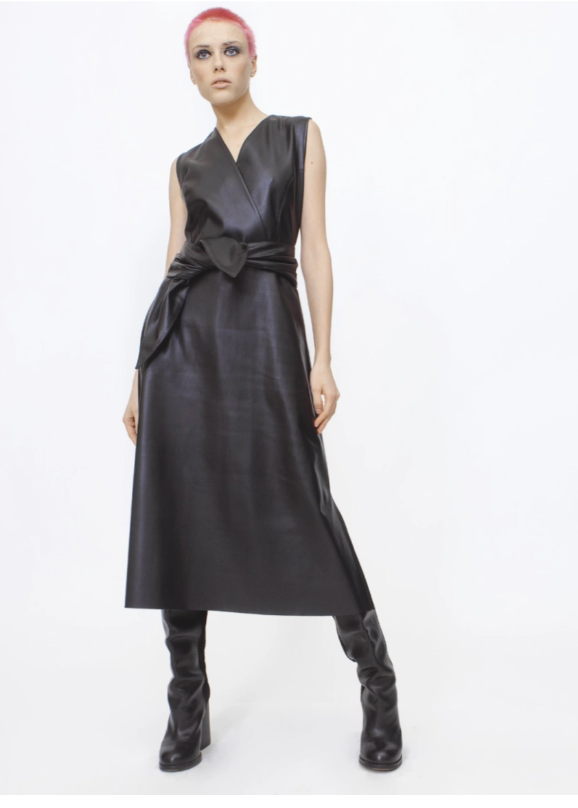 A model with short hair stands in the Black Sleeveless Faux Leather Dress from Julia Allert