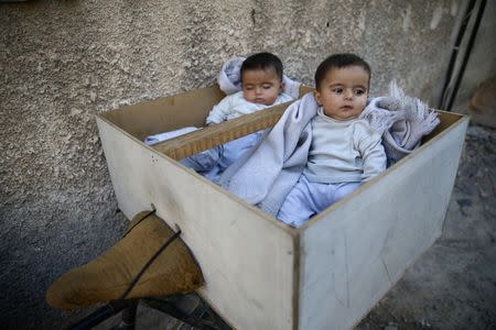 Five-month-old twins Farah and Marah wait for their parents to receive milk distributions from a medical center in the Hamoria area, in the eastern Damascus suburb of Ghouta, Syria, October 25, 2017. REUTERS/Bassam Khabieh