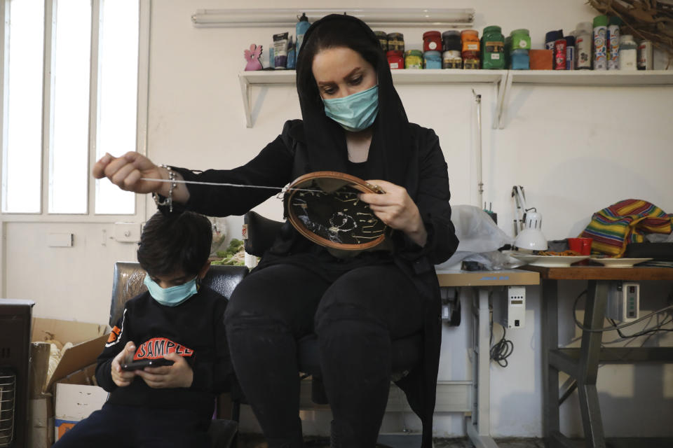 Elaheh Rahimi embroiders at a workshop of Bavar charity in Tehran, Iran, Monday, Nov. 23, 2020. As the coronavirus pandemic ravages Iran, a women’s group hopes to empower its members by helping them make and sell face masks. (AP Photo/Vahid Salemi)